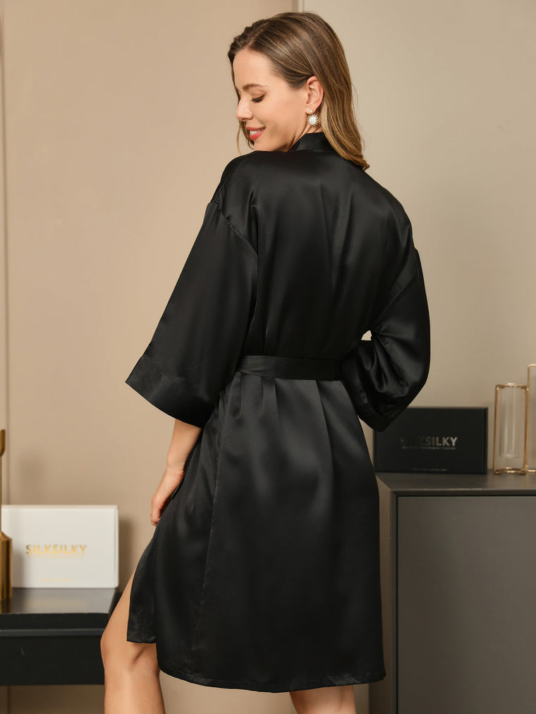 Woman in a black mulberry silk 3/4 sleeve kimono wrap robe, tied at the waist.