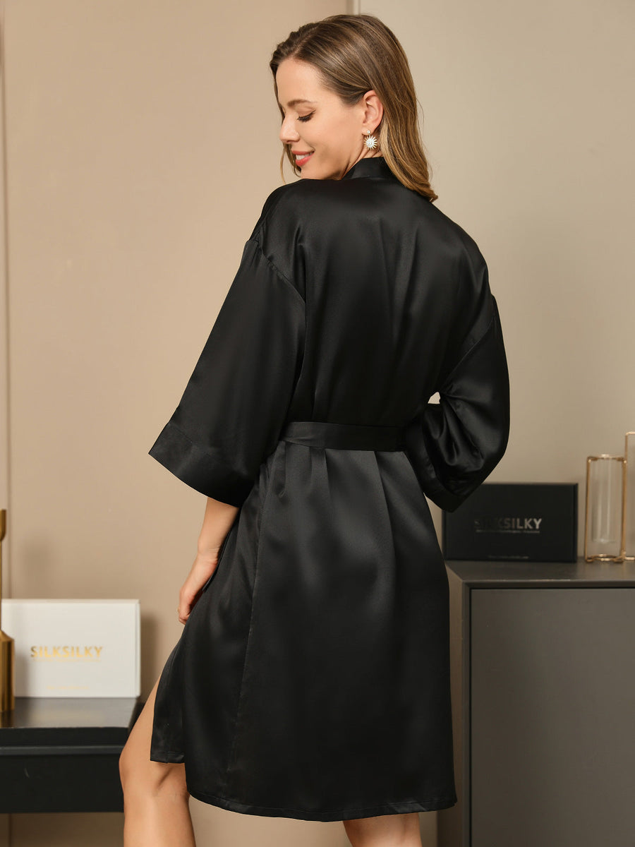 Woman in a black mulberry silk 3/4 sleeve kimono wrap robe, tied at the waist.