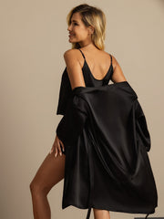 Woman in black mulberry silk robe and cami shorts set, elegant loungewear.