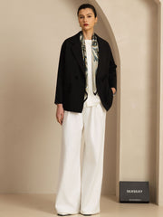 Woman wearing a 100% Mulberry silk abstract floral pattern square scarf with a black blazer and white pants.