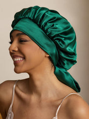 Two-tone mulberry silk casual bonnet in emerald green with long ribbons, worn by a smiling woman.