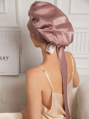 Two-tone mulberry silk casual bonnet with long ribbons, worn by a woman in a silk nightgown.