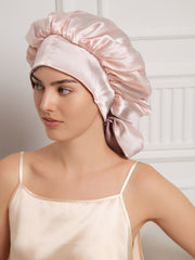 Two-tone mulberry silk bonnet in pink and light brown, with long ribbons, worn by a woman.