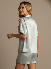Women's light blue mulberry silk short sleeve pajama set with collared top and matching shorts.