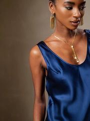 Navy blue mulberry silk sleeveless U-neck top on a model, featuring a gold necklace and earrings.