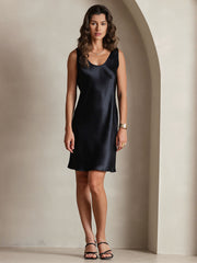 Woman wearing a black mulberry silk U-neck sleeveless short dress.