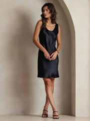 Woman in a black mulberry silk sleeveless U-neck short dress.