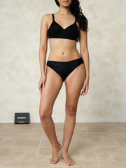 Black mulberry silk classic bikini panty with bow, worn by a woman.