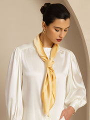 Elegant woman wearing a 90x90cm classic square mulberry silk scarf in a soft yellow hue, tied at the neck.