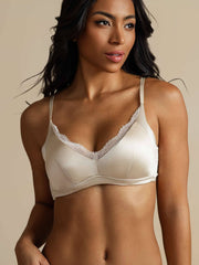 Woman wearing a champagne 100% mulberry silk wireless bra with delicate lace trim.