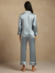 Women's light blue mulberry silk pajama set with long sleeves and white contrast piping, seen from the back.