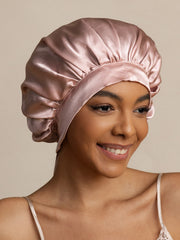 Elegant pink mulberry silk bonnet with long ribbons on a smiling woman.