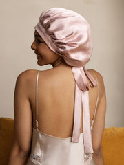 Pink mulberry silk bonnet with long ribbons on a woman.