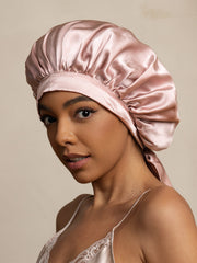 Elegant pink mulberry silk bonnet with long ribbons, worn by a woman.