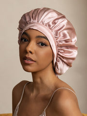 Elegant blush pink mulberry silk bonnet with long ribbons on a woman.