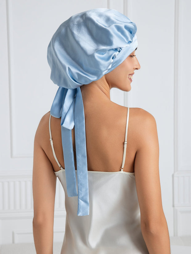 Light blue mulberry silk bonnet with long ribbons on a woman wearing a silk top.