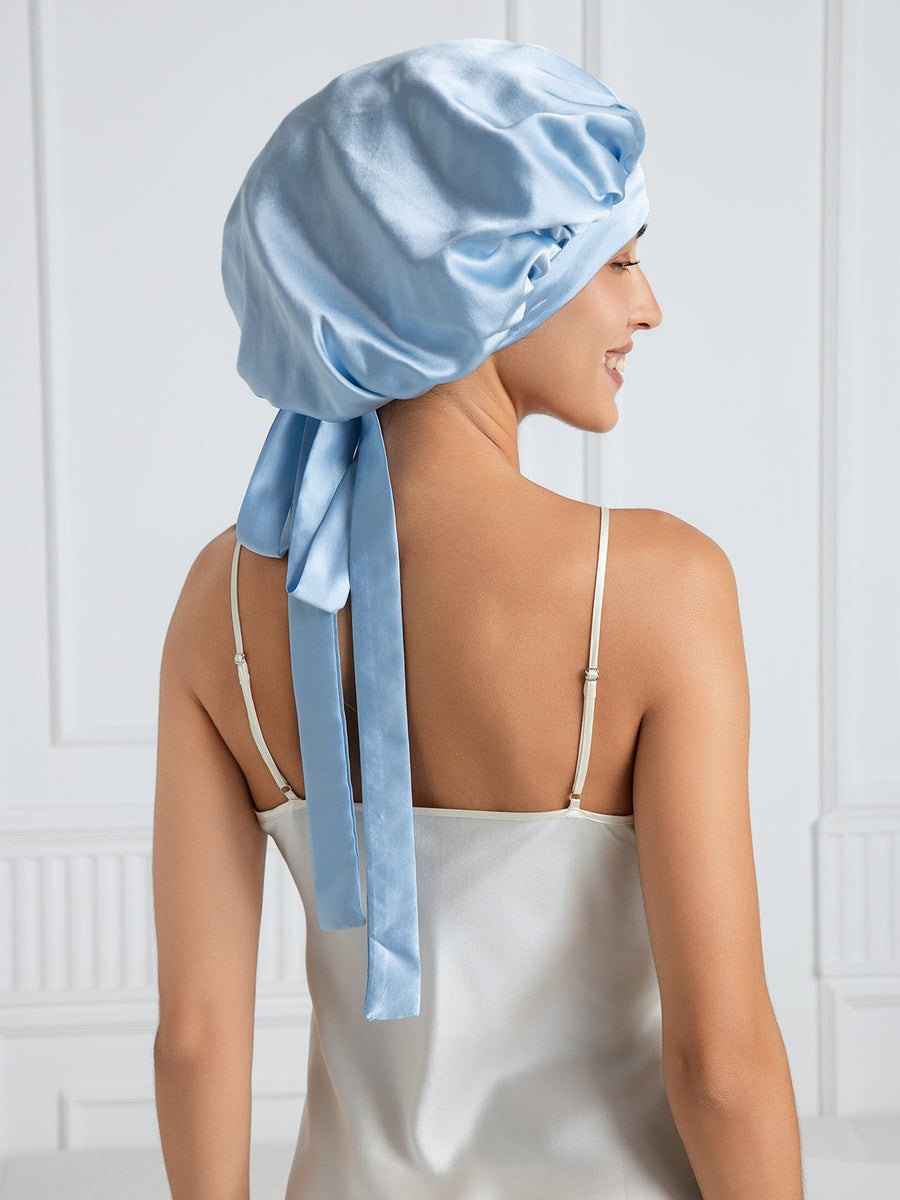 Light blue mulberry silk bonnet with long ribbons on a woman wearing a silk top.