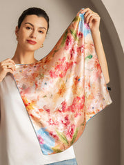 Woman holding a 100% Mulberry silk floral bliss square scarf, 53x53cm, with vibrant red and orange flowers.