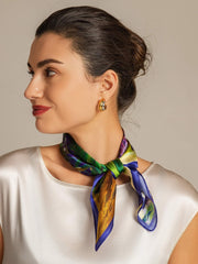 Woman wearing a mulberry silk floral oil painting square scarf, tied around her neck, with a white top.