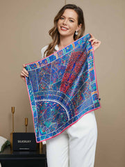 Woman holding a blue mulberry silk floral pattern scarf with pink trim, 53x53cm.