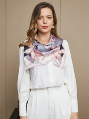 Woman wearing a pink and grey floral mulberry silk scarf with a white shirt.