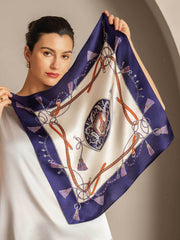 Woman holding a mulberry silk floral square scarf with a navy blue and white equestrian pattern.