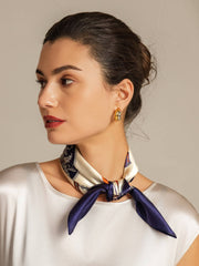Woman wearing a white and navy blue mulberry silk floral square scarf, tied at the neck.