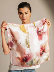 Mulberry silk floral square scarf with pink trim, held by a woman.