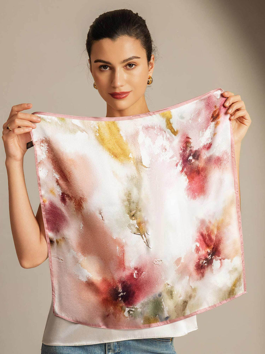 Mulberry silk floral square scarf with pink trim, held by a woman.