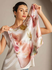 Mulberry silk floral square scarf with pink trim, held by a woman.