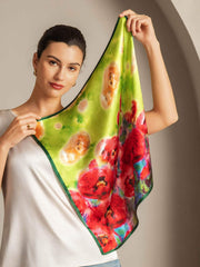 Woman holding a vibrant mulberry silk scarf with red flower impression design on a lime green background.