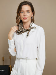 Woman wearing a mulberry silk geometric pattern square scarf in brown and white, paired with a white shirt.