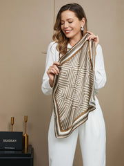 Woman holding a brown and white mulberry silk geometric pattern square scarf.