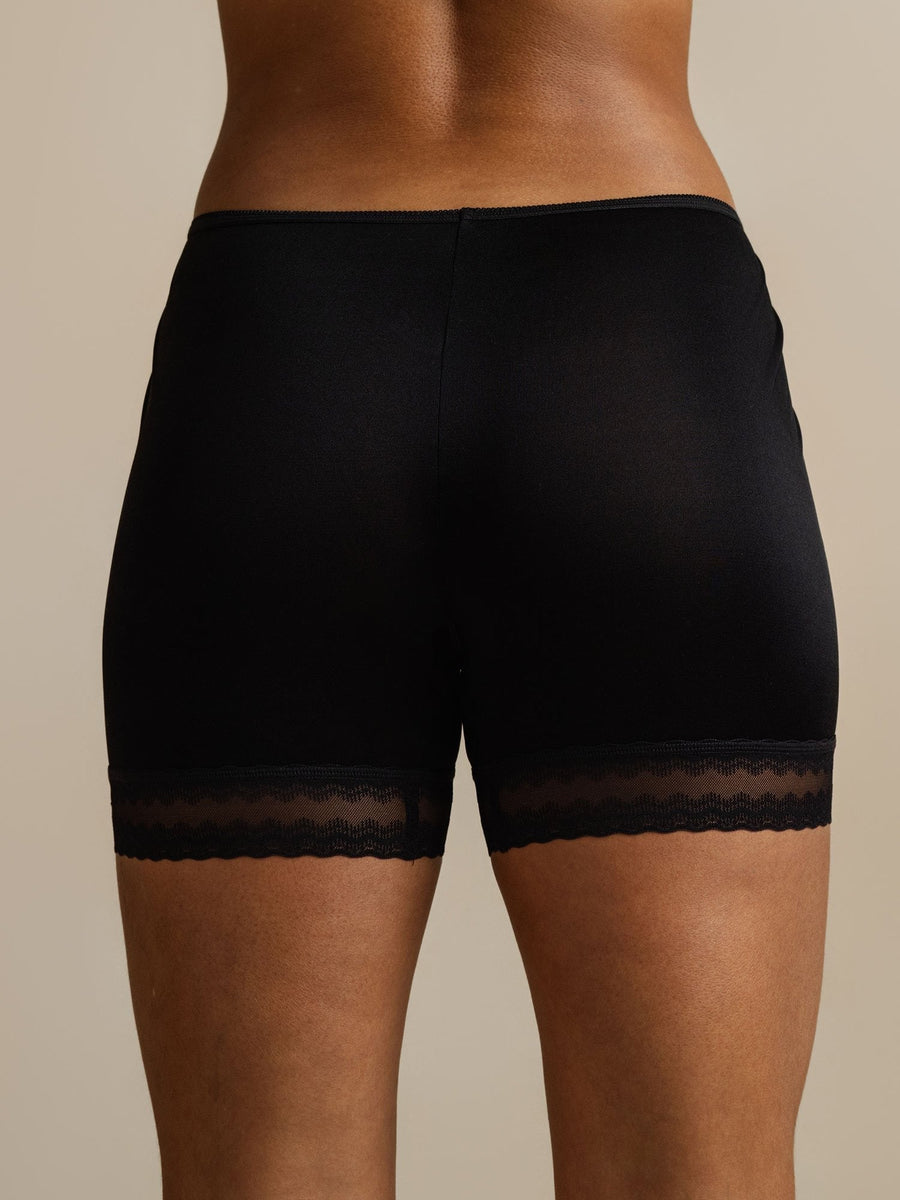 Black mulberry silk anti-chafing shorts with lace trim, worn by a person from behind.
