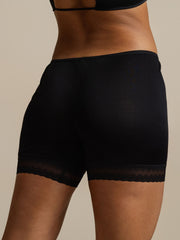 Black mulberry silk anti-chafing shorts with delicate lace trim, worn by a woman.
