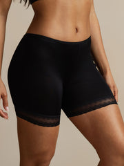 Black mulberry silk anti-chafing shorts with delicate lace trim, worn by a woman.