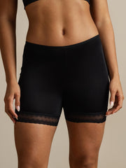 Black mulberry silk anti-chafing shorts with delicate lace trim, worn by a woman.