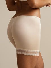 Nude mulberry silk anti-chafing shorts with delicate lace trim, worn by a woman.