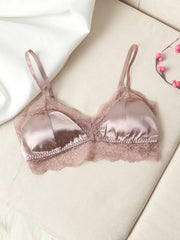 Blush pink mulberry silk lace-trimmed bra with adjustable straps on a cream sofa.