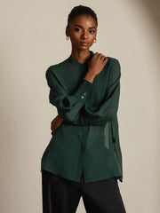 Women's sheer mulberry silk long sleeve blouse in deep forest green, styled with black pants.