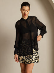 Woman wearing a black sheer mulberry silk long sleeve blouse with a leopard print skirt.