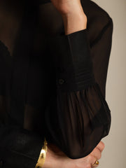 Black sheer mulberry silk long sleeve blouse with buttoned cuffs and a gold bracelet.