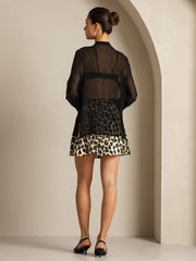 Woman in black sheer mulberry silk long sleeve blouse over leopard print skirt.