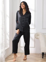 Smiling woman in black mulberry silk long sleeve women's pajamas set with button-up top and pants.