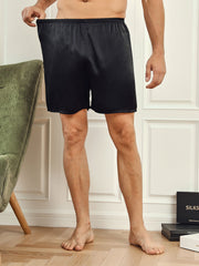 Men's black mulberry silk lounge shorts with elastic waist, shown on a model.