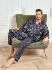 Men's navy mulberry silk pajamas with gold chain print, long sleeves, and pants, worn by a man in a chair.