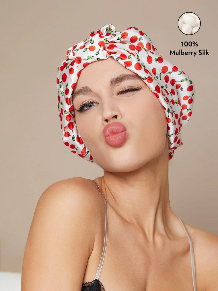 White 100% Mulberry silk night turban bonnet with red cherry print on a woman.