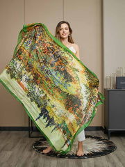Woman holding a large mulberry silk scarf with a vibrant oil painting tree design and green border.