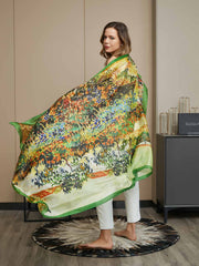 Woman modeling a large mulberry silk scarf with a vibrant oil painting landscape design and green border.