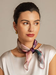 Woman wearing a 53x53cm mulberry silk square scarf with a soft, abstract pattern in pink, purple, and teal.
